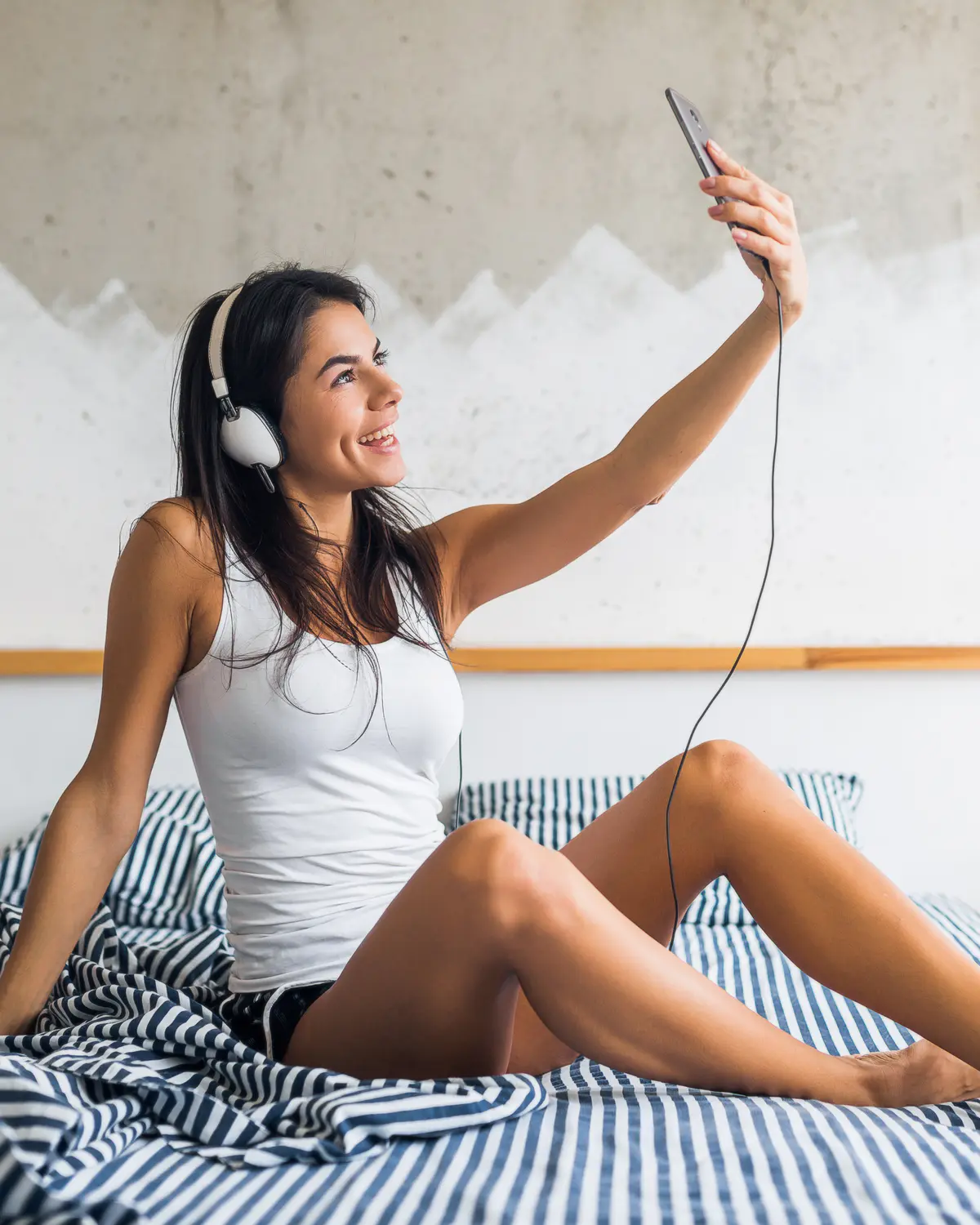 Creator OnlyFans al lavoro con smartphone e cuffie durante la gestione quotidiana del profilo